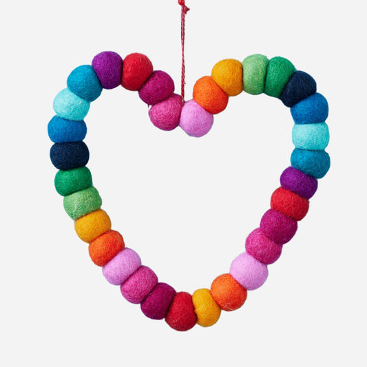 Colorful heart-shaped wreath made of felt balls on a light blue wooden background