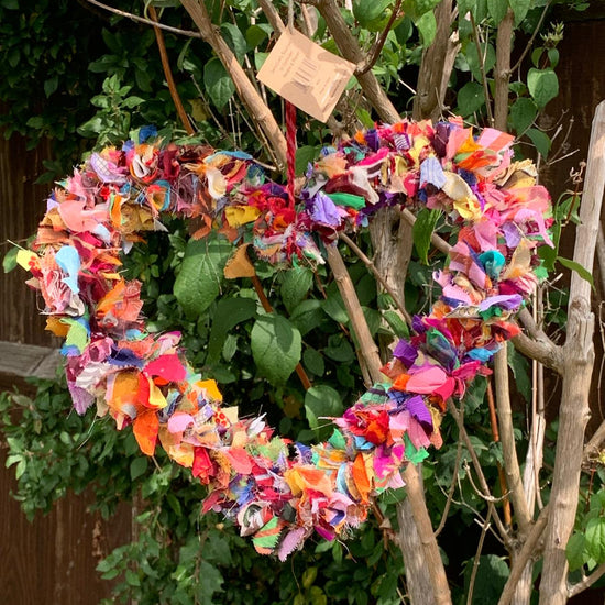 hanging, colourful, heart-shaped wreath made from recycled sari offcuts