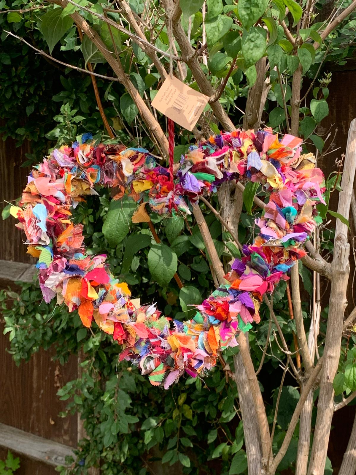 hanging, colourful, heart-shaped wreath made from recycled sari offcuts