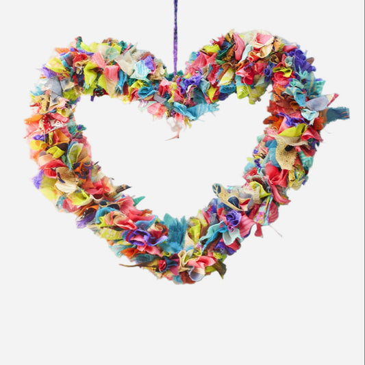 Colorful recycled sari fabric heart-shaped hanging wreath on a light grey background