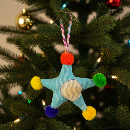 Colorful star-shaped decoration with pom-poms on a Christmas tree