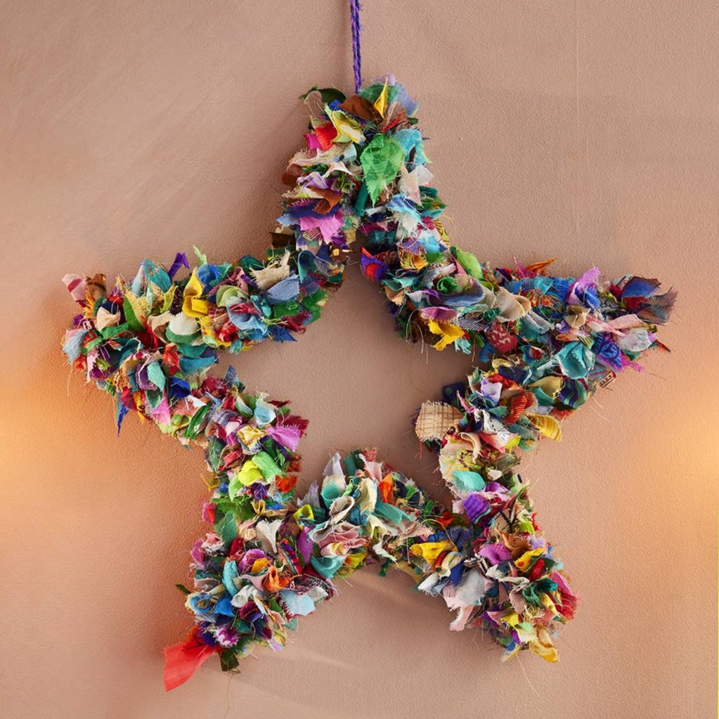 Colorful star-shaped wreath hanging on a beige wall