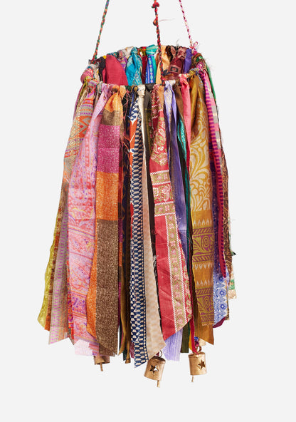 Colorful fabric hanging windchime with bells on a grey background