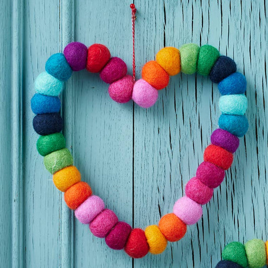 Colorful heart and star-shaped decorations made of yarn on a blue wooden background