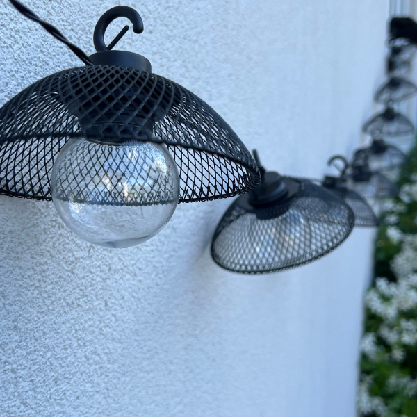 solar string lights with black mesh lanterns, clear round bulbs, black wire and LED lights (not visible)