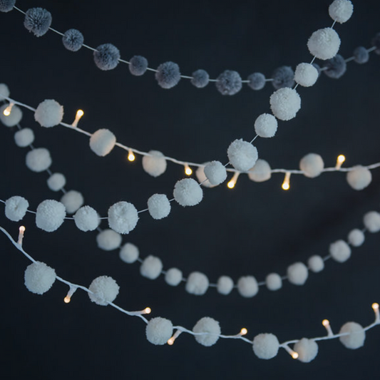 String lights with white pom-pom balls against a dark background