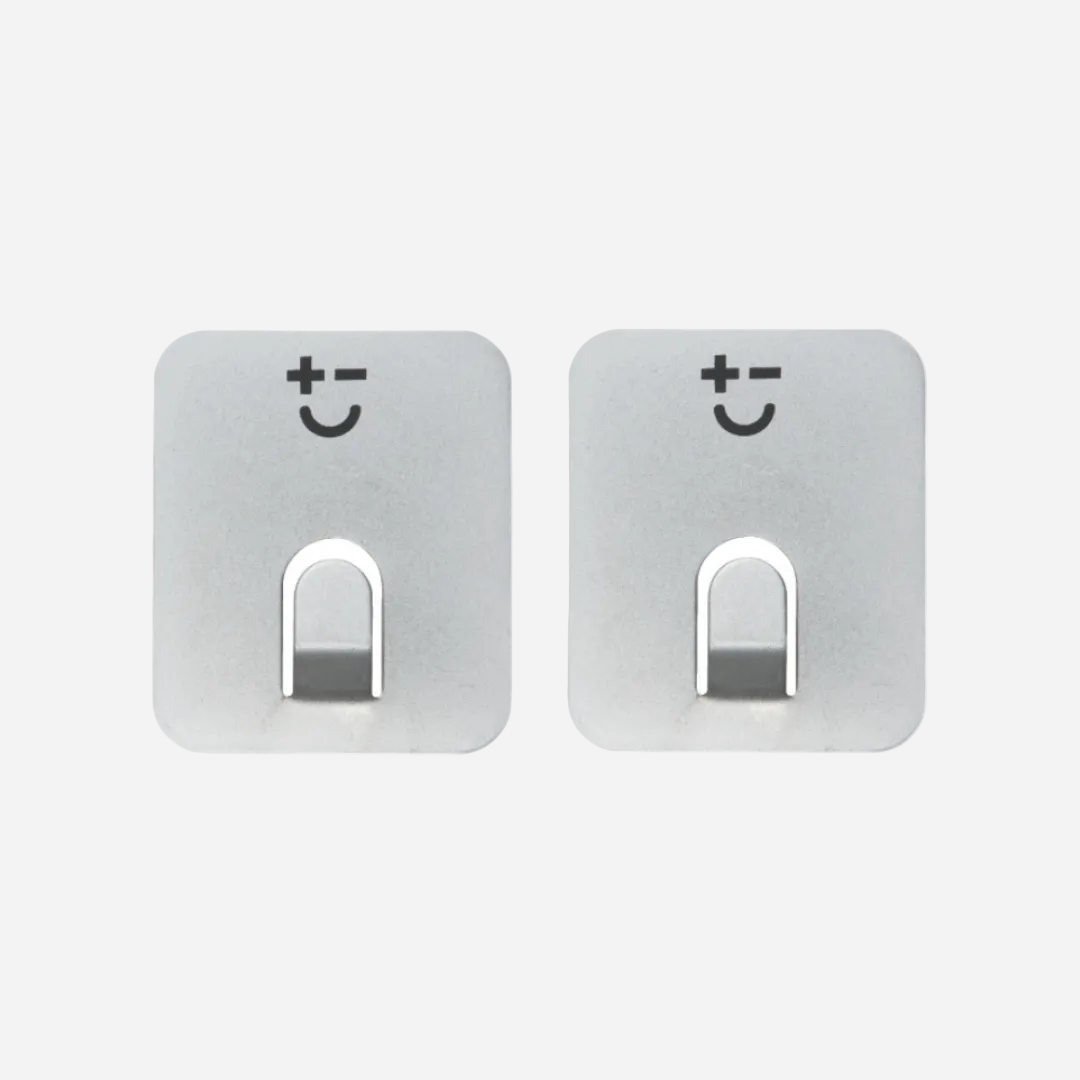 Two stainless steel magnets with smiley face designs on a light grey background