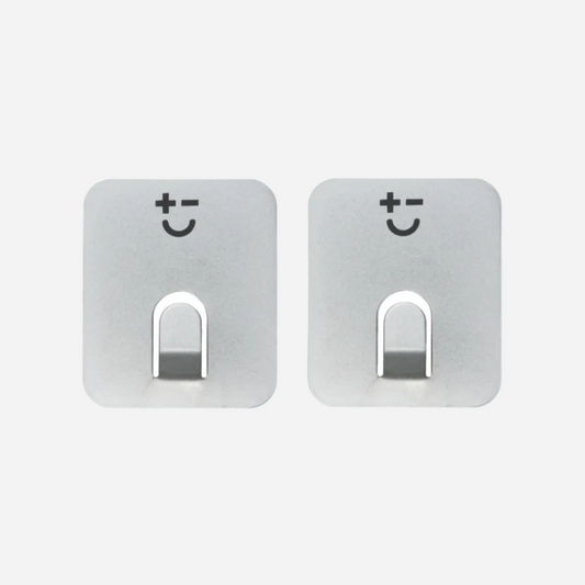 Two stainless steel magnets with smiley face designs on a light grey background