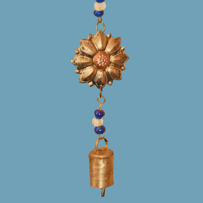 Decorative hanging wind chime with a sunflower design and bell on a blue background