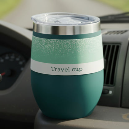 PEtrol blue travel cup with a speckled pattern and white paper band on a car dashboard