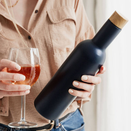female holding glass of pink wine and navy insulated travel wine bottle