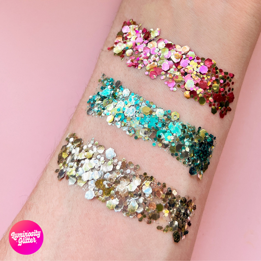 Colorful glitter streaks on a person's arm with 'Luminosity Glitter' logo.