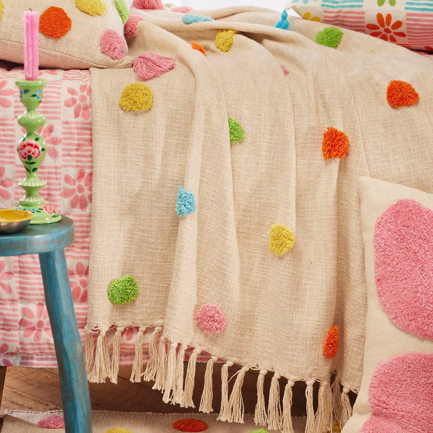 Decorative bedspread with colourful tuft dots on a bed in a bright room.