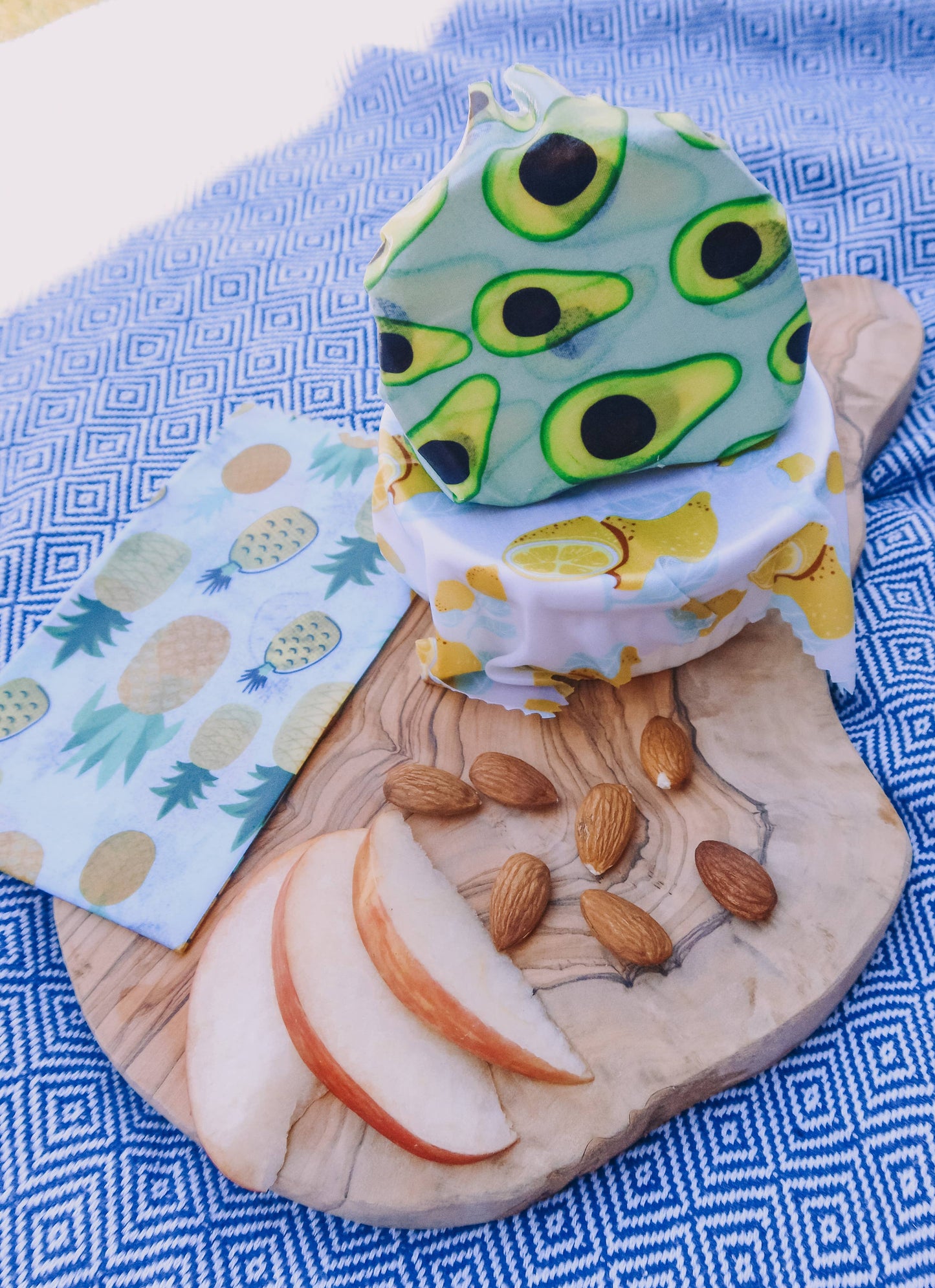 Avocado-themed vegan wax food wrap on a wooden board with fruits and nuts