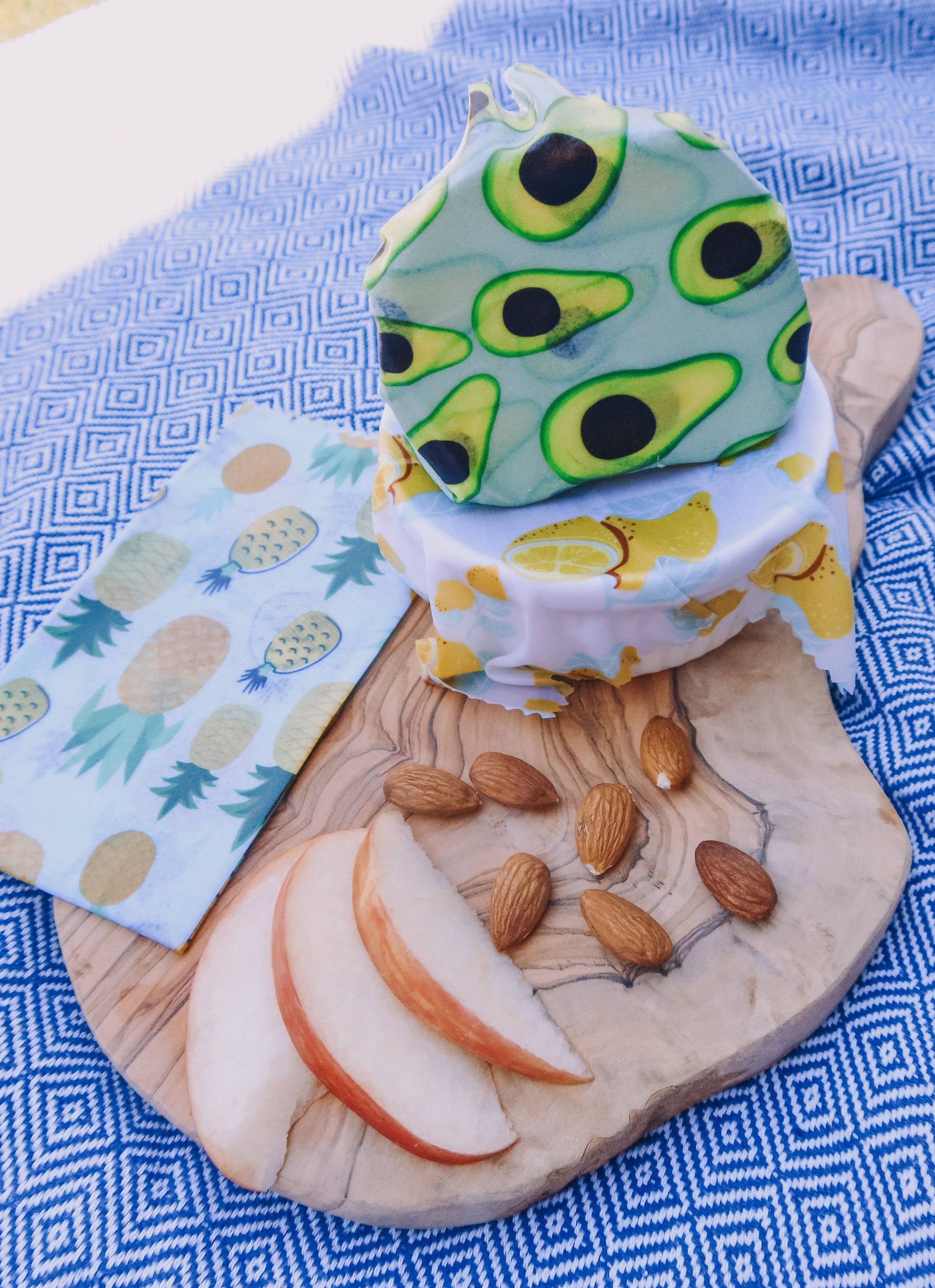 Avocado-themed vegan wax food wrap on a wooden board with fruits and nuts