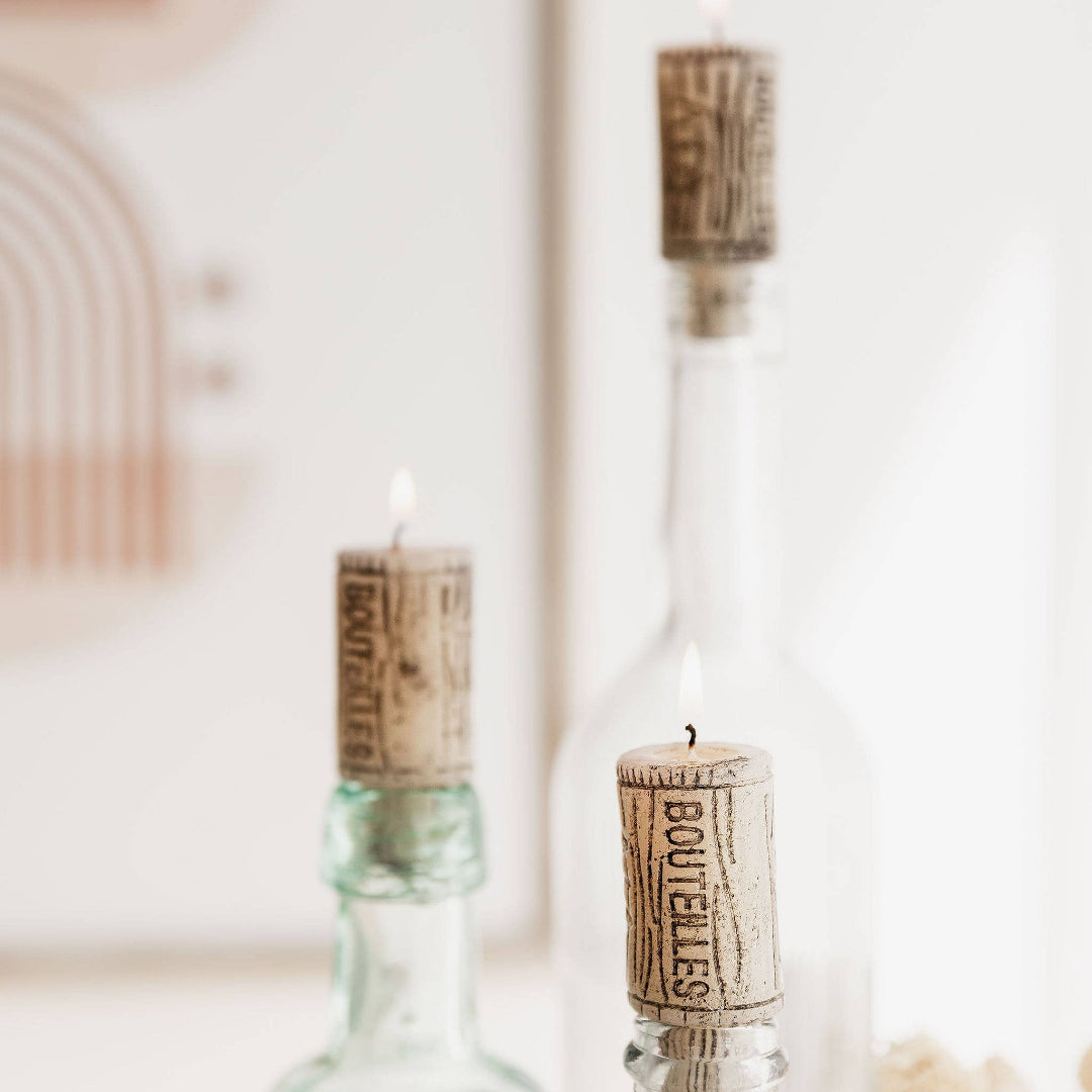 three glass bottles with cork candle stoppers on a blurred background