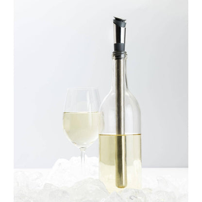Clear wine bottle with cihll stick and wine pourer and a glass of white wine on a light gray background