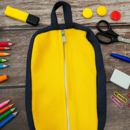 Yellow pouch with navy trim and central zip surrounded by school supplies on a wooden surface